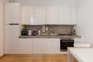 a kitchen with white cabinets and a microwave at Nice Flat Milan 50m Station! in Milan