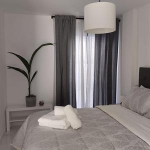 a bedroom with a bed with white pillows and a plant at Apartamento SUN GATE in Jerez de la Frontera