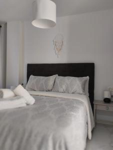 a white bedroom with a large bed with a black headboard at Apartamento SUN GATE in Jerez de la Frontera +19 photos