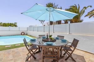 a table with chairs and an umbrella next to a pool at Villa Palacios Herrero in Tahiche