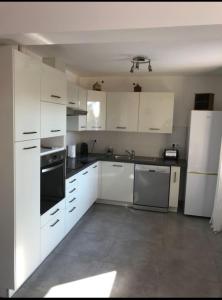 una cucina con mobili bianchi e un frigorifero bianco di Charmante Maisonnette t2bis plaine de Calenzana a Calenzana Altre 4 foto