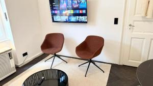 two chairs in a room with a tv on the wall at Exklusive Wohnung im Herzen Münchens in Munich