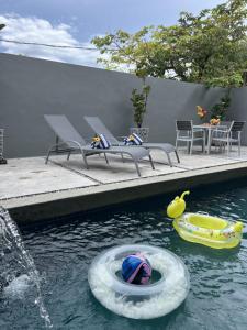 a pool with two inflatables in the water at The Langkawi Luxury - Private Pool Villas & Rooftop Sunset in Pantai Cenang