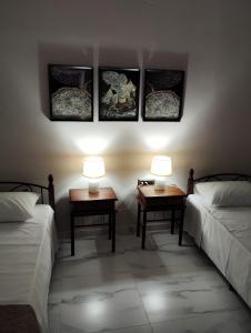a room with two beds and two tables with lamps at Denis apartment in Argostoli
