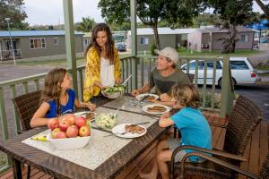 a woman and two children sitting at a table eating food at Discovery Parks - Harrington in Harrington