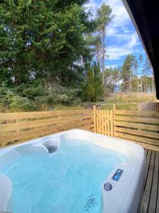 a hot tub on a deck with a fence at kaoglen Wild-Hot tub-Cairngorms-Pet Friendly in Balnald