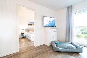 a white living room with a couch and a tv at Seebreeze 50 2 N in Wangerland