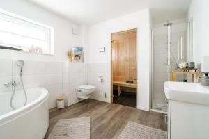 a bathroom with a tub and a sink and a toilet at Seebreeze 50 2 N in Wangerland +24 photos