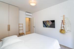 a white bedroom with a white bed and a ladder at Apartments Irena in Cavtat