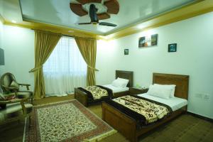 a bedroom with two beds and a ceiling fan at Town Inn Chitral Guest House in Motehiānāndeh
