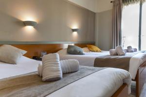 a hotel room with three beds with pillows on them at Anesis Hotel in Kozani