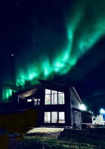 une maison avec l'aurore boréale dans le ciel dans l'établissement Arctic Villa, à Kvaløya