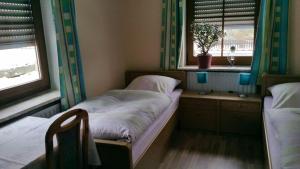 a small bedroom with two beds and two windows at Haus Eva in Eslarn