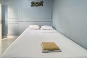 - un lit blanc avec une serviette brune dans l'établissement Andung Residence Lampung RedPartner, à Bandar Lampung