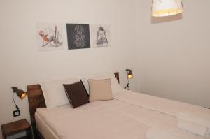 a bedroom with a white bed with two pictures on the wall at AS Apartments in Kopaonik
