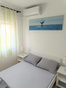 a white bedroom with a bed and a whale picture on the wall at Apartment Mario, Novalja in Novalja