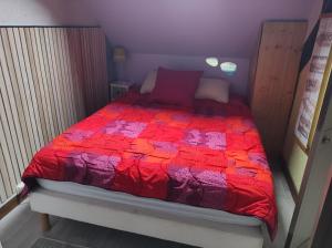 Bett mit einer roten Bettdecke in einem Zimmer in der Unterkunft ty anna in Le Palais