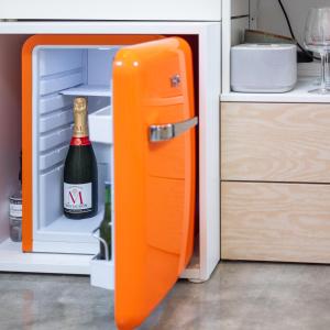 an orange refrigerator with a bottle of champagne in it at Boat suite - A Unique Houseboat Stay in Amsterdam in Amsterdam +20 photos