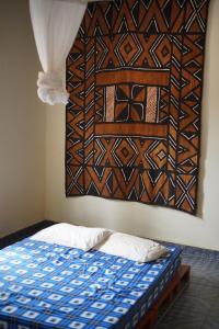 a bedroom with a bed with a painting on the wall at Dafa Tanga Lodge in Sanyang +13 photos