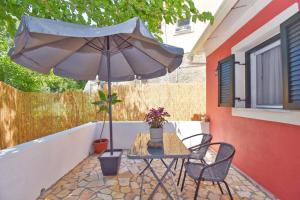 a table and chairs with an umbrella on a patio at Casa Campagnolo in Corfu