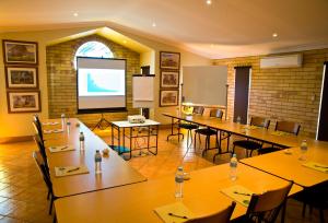 a classroom with tables and chairs and a projection screen at Starlight Motor Inn in Roma
