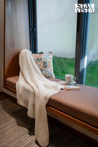 a blanket sitting on a bench next to a window at StayVista at Ember Home with Balcony, Meals Available in Mussoorie +13 photos