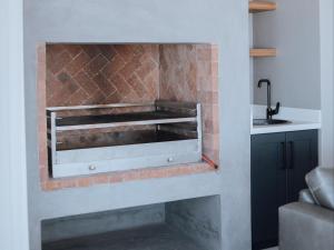 a brick fireplace in a kitchen with a sink at KnusRus in Jongensfontein