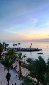a beach with palm trees and a boat in the water at Bello Horizonte Apartman 4B in Salou