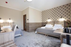 a hotel room with two beds and a desk at Hotel Maksymilian in Krakow