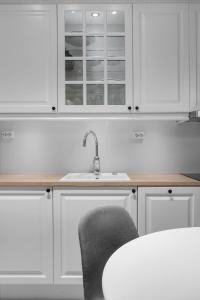 a kitchen with white cabinets and a sink and a chair at Leilighet midt i sentrum in Tromsø