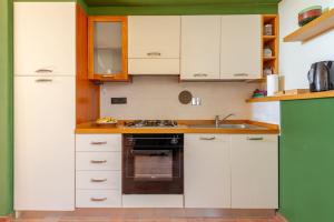 a kitchen with white cabinets and a stove top oven at Agriturismo La Torre dell'Oliveto in Agello