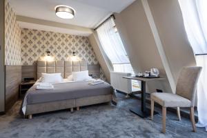 a bedroom with a bed and a desk and a chair at Hotel Maksymilian in Krakow