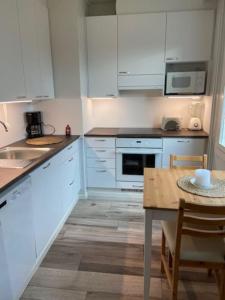 a kitchen with white cabinets and a wooden table at Käytännöllinen yksiö rauhallisella alueella! in Hyvinkää