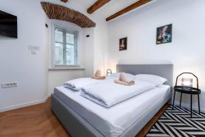 a white bedroom with a large bed and a window at Corso Apartments in Rijeka