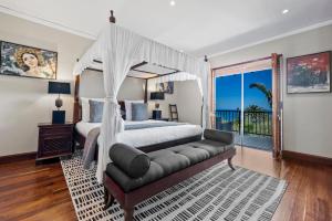 a bedroom with a canopy bed and a couch at The Cape Bali Luxury Villa with Ocean Views in Camps Bay in Cape Town +117 photos
