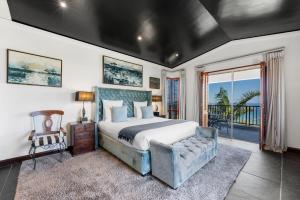 a bedroom with a bed and a couch and a window at The Cape Bali Luxury Villa with Ocean Views in Camps Bay in Cape Town
