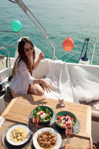 Una niña sentada en un barco con platos de comida. en Luxury Sailing Cruises in Athens with Traditional Greek Cuisine and Drinks, en Atenas