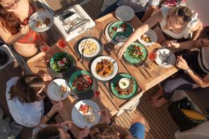 un grupo de personas sentadas alrededor de una mesa con comida en Luxury Sailing Cruises in Athens with Traditional Greek Cuisine and Drinks, en Atenas