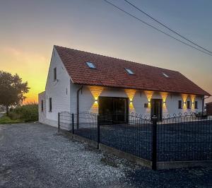 a white building with a red roof and a fence at De Viervoeters Hoeve in Ruiselede