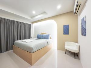 un dormitorio con una cama y una silla en The Seathru Koh Larn, en Pattaya central