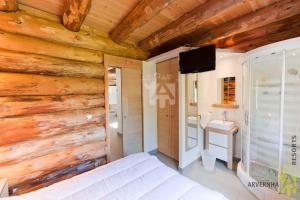 1 dormitorio con pared de madera, cama y TV en La Fuste du Lac, en Chambon-sur-Lac