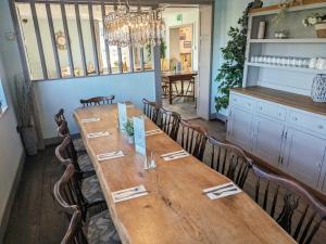 a long wooden table in a room with chairs at The Ship Inn in Dymchurch