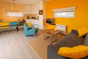 a living room with a couch and a table and a kitchen at Lucky Bay - Ecohuisjes Terschelling in Midsland +14 photos
