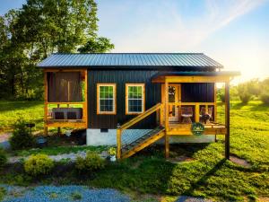 ein winziges Haus mit einer Terrasse auf einem Feld in der Unterkunft Romantic Cabin - The Woodland Nook in Sevierville
