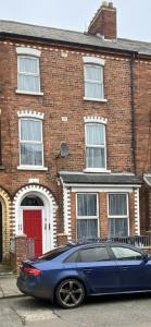 a blue car parked in front of a brick house at Twin Room - Botanic, Belfast in Belfast