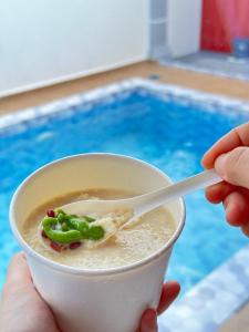 a person holding a cup of soup with a spoon at 803 Villa AFamosa Villa in Kampong Ulu Pegoh