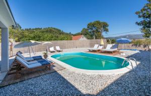 a swimming pool with chairs and an umbrella and a patio at Amazing Home In Kula Norinska With Wifi in Kula Norinska