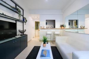 a living room with a white couch and a tv at AIOLOS glyfada centre apartment 2 in Athens
