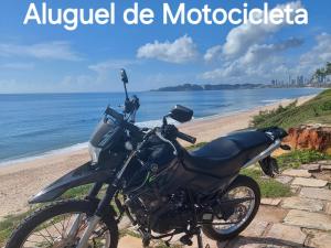 a motorcycle parked next to a beach with the words ayuedev de modoc at Casas 5 min a pé da praia in Natal