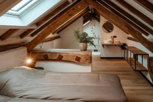 an attic bedroom with a bed and wooden beams at Recreatie Landgoed Terlingerhoeve in Noorbeek